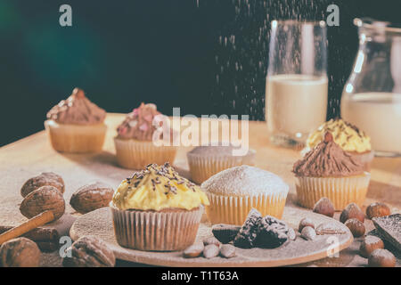 Frische Muffins und Cupcakes bestreut mit Zucker auf einem Holzbrett - Bild Stockfoto