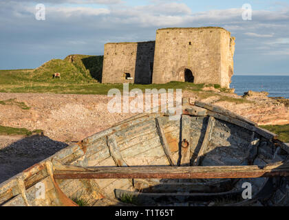Der innere Bogen eines verlassenen Fischerboot mit der Ruine einer alten Mühle im Hintergrund, an einem sonnigen Tag in Boddin, Angus, Schottland Stockfoto