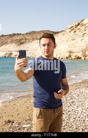 Junger Mann im blauen T-Shirt auf dem Smartphone und eine selfie. Stockfoto