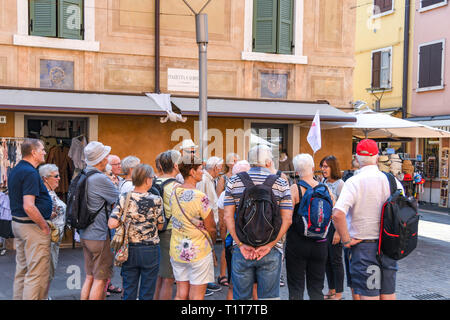 Gardasee, Italien - September 2018: Tour Guide erklärt die lokale Geschichte zu einer Gruppe von Touristen in der Stadt Garda am Gardasee. Stockfoto