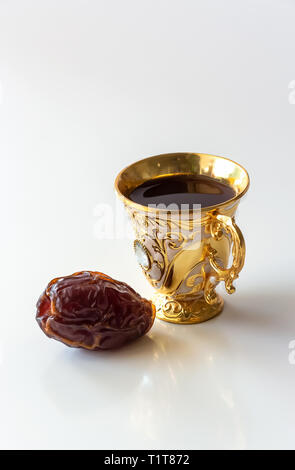Luxus Arabisch Goldene Tasse schwarzen Kaffee oder Tee und Datteln isoliert weißer Hintergrund. Ramadan Konzept. Stockfoto