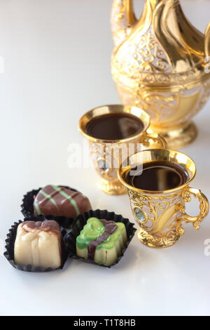 Stillleben mit traditionellen Goldenen arabischen Kaffee mit dallah, Tasse Schokolade und Süßigkeiten. Weißer Hintergrund. Stockfoto
