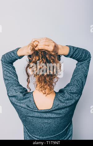 Rückansicht der jungen Frau mit glänzenden lockiges Haar ihr Pferdeschwanz Frisur, auf weißem Hintergrund. Stockfoto