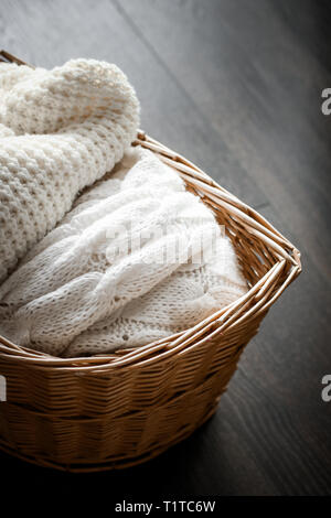 Strickwaren, fabric Texturen und rustikalen Lebensstil Konzept - aus Gewirken Winterkleidung in einem Korb Stockfoto
