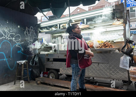 Eine Südamerikanische Frau verkaufen Gegrilltes Fleisch und andere Lebensmittel, die aus einem Warenkorb gerade weg von Roosevelt Ave. und ein paar Meter vom erhöhten und U-Bahn. NYC Stockfoto