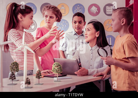 Dunkelhaarige Lehrerin sitzt mit ihrem Tablet Stockfoto