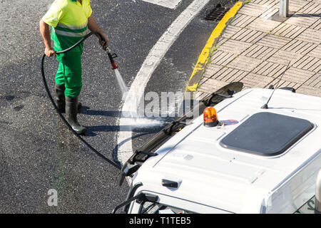 Arbeitnehmer Reinigung der Straße und Straße Gehweg mit hohem Druck Wasser. Öffentliche Wartungskonzept Stockfoto