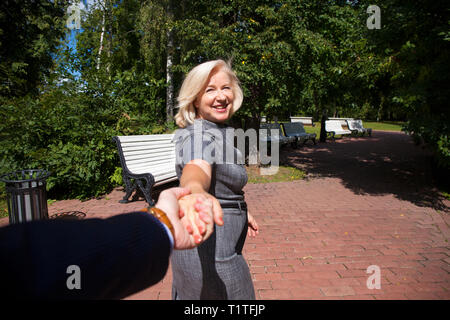 Folgen Sie mir. Porträt der schönen blonden Frau mittleren Alters im Sommer Park Stockfoto