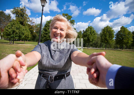 Folgen Sie mir. Porträt der schönen blonden Frau mittleren Alters im Sommer Park Stockfoto