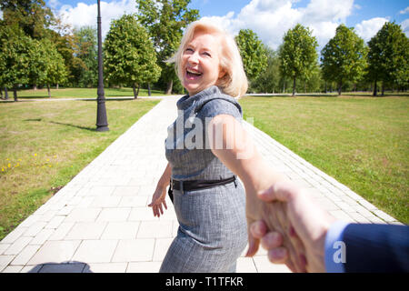 Folgen Sie mir. Porträt der schönen blonden Frau mittleren Alters im Sommer Park Stockfoto