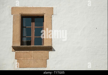 Einsame kleine Fenster mit Stein garnieren auf einer Wand in Weiß an Caceres gemalt. Eine charmante Stadt mit einem vollständig erhaltenen Altstadt in Spanien. Stockfoto