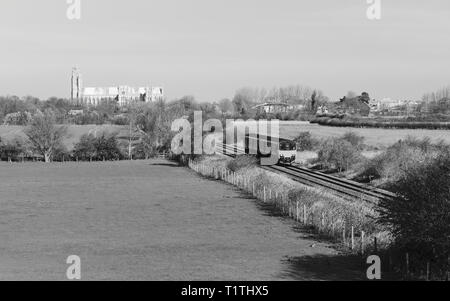 Eine Eisenbahn Zug Schnitte durch ländliche Landschaft an einem strahlenden Frühlingstag mit alten Münster am Horizont in der Nähe von Beverley, Yorkshire, Stockfoto