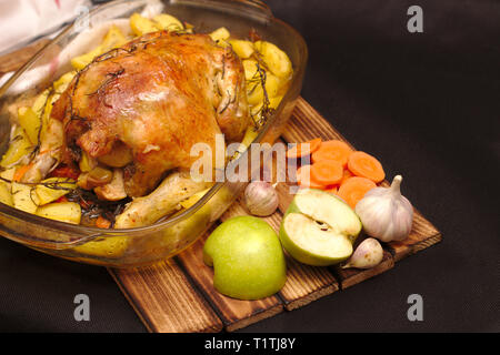 Im Ofen gebackene knusprige Kruste gefüllte Huhn auf einem Teller mit Kartoffeln und Äpfel Stockfoto
