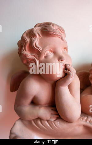 Eine hübsche Cherub lehnte sich auf seinen Armen und Blick und lehnte sich auf der Shell Stockfoto