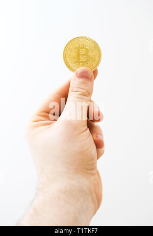 Mann hält physische Version von golden Bitcoin auf weißem Hintergrund. Stockfoto
