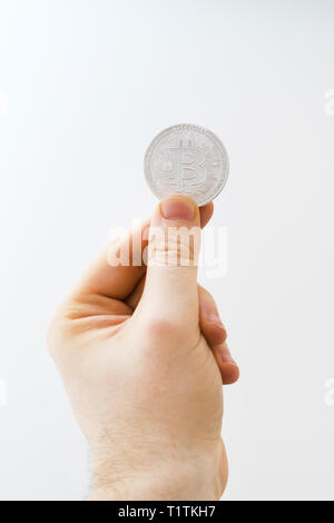 Mann hält physische Version von Silber bitcoin auf weißem Hintergrund. Stockfoto