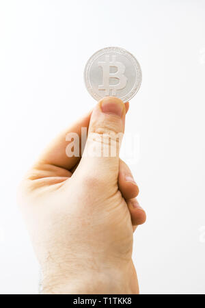 Mann hält physische Version von Silber bitcoin auf weißem Hintergrund. Stockfoto