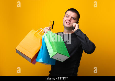 Foto von Mann Shopper mit Papiertüten, Bankkarte und Telefon in der Hand Stockfoto