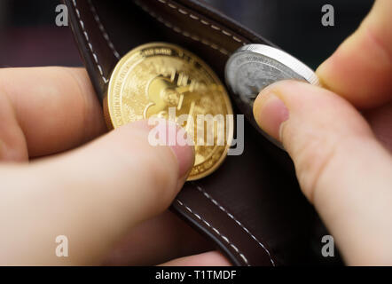 Mann hält physische Version von goldenen und silbernen Bitcoins. Stockfoto
