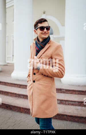 Glückliche junge stilvollen Mann zu Fuß in der Stadt. Hübscher Kerl trägt klassische Kleidung und Accessoires. Street Fashion. Stockfoto