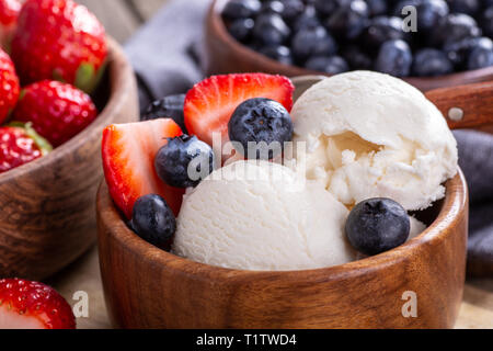 Nahaufnahme von Vanilleeis mit frischen Blaubeeren und Erdbeeren in eine hölzerne Schüssel Stockfoto