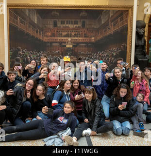Eine Gruppe von französischen Studenten ein Foto von sich vor dem Gemälde 'Dentwickelte sich das Parlament durch die Graffiti Künstler Banksy, der auf der Bristol Museum ist. Stockfoto