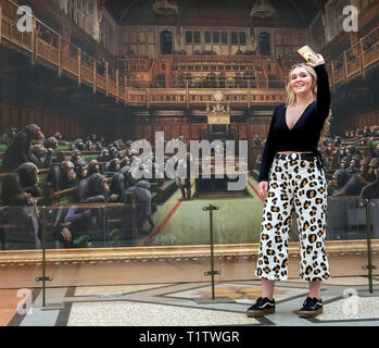 Isabelle Schofield nimmt ein Foto von sich vor dem Gemälde 'Dentwickelte sich das Parlament durch die Graffiti Künstler Banksy, der auf der Bristol Museum ist. Stockfoto