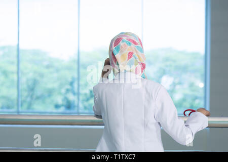 Zurück von einer Ärztin das Fenster mit Blick beim Denken an etwas Stockfoto