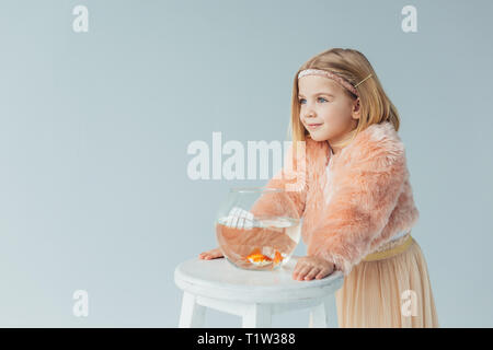 Cute kid in Fellimitat Mantel und Rock mit Fishbowl entfernt auf grau, isoliert Stockfoto