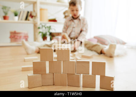 Kleines Kind auf dem Boden saß. Pretty Boy palying mit Holzwürfeln zu Hause. Konzeptionelle Bild mit Text oder negativen Raum und Mock-up für Ihren Text Stockfoto