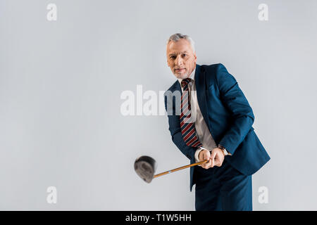 Selektiver Fokus der fröhlichen reife Geschäftsmann holding Golf Club, während Sie isoliert auf Grau Stockfoto