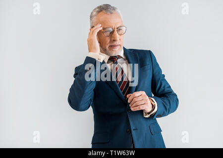 Reifen Geschäftsmann in Anzug in Kopfschmerzen beim Stehen auf Grau isoliert Stockfoto