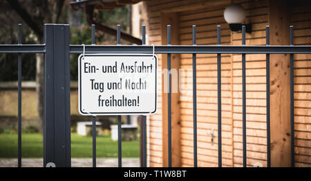 Schild Einfahrt halten sich Tag und Nacht in deutscher Sprache auf einem schwarzen Metallzaun Stockfoto
