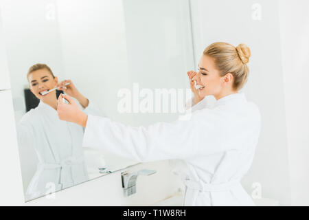 Selektiver Fokus der schönen Frau in weißen Bademantel Zähneputzen und die selfie Stockfoto