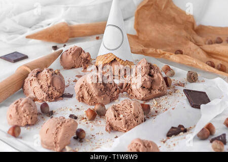 Haselnuss und Schokolade Eis Kugeln mit Schokolade dekoriert und zerbröckelt Haselnüsse und ganze Haselnüsse in der Schale Stockfoto