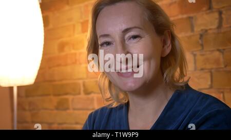 Close-up Portrait von Senior kaukasischen Dame beobachtet lächelnd in die Kamera in gemütlicher Atmosphäre. Stockfoto