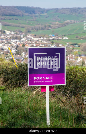 Lila Ziegel Haus für Verkauf Zeichen in der offenen Landschaft oberhalb des Dorfes Sidford, nr Honiton, Devon, Großbritannien Stockfoto