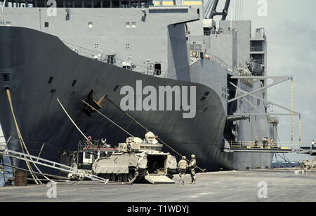 29. Oktober 1993 das riesige Transportschiff der US-Marine Administration, USNS Denebola, liegt im neuen Hafen in Mogadischu, Somalia. Mehrere Soldaten der US-Armee stehen auf der Ausfahrt auf der Hafenseite und um einen M2 Bradley IFV auf der Uferseite, in der Nähe seines Bogens. Ein weiterer M2 Bradley steht am Heck. Stockfoto