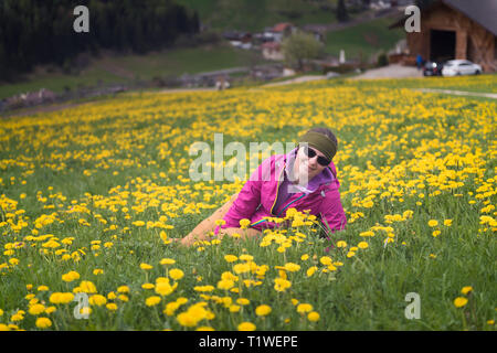 Aktiv gesund Frau in Ruhe auf die schöne Wiese mit Blumen bedeckt. Portrait von Glücklich lächelnde junge Frau Ruhe der Berge beim Clearing Stockfoto