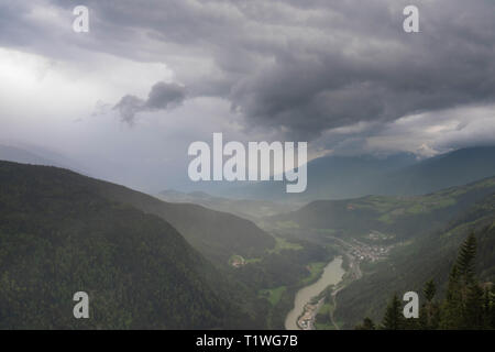 Malerische Luftaufnahme auf Dörfer im Dolomiten mit Berge in Wolken auf Hintergrund und Wiesen im Vordergrund. Ort: Dolomiten, Tyr Stockfoto