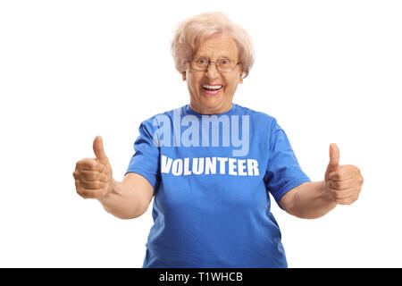Lächelnde ältere weibliche Ehrenamtliche in einem blauen T-Shirt geben Daumen bis isoliert auf weißem Hintergrund Stockfoto