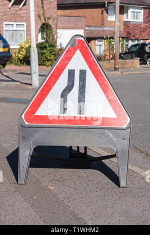 Ein temporäres Schild (Straße auf der linken Seite verengt) auf dem Gehweg platziert Stockfoto