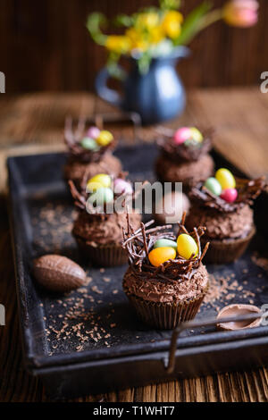 Osternest Cupcakes mit Schokolade, Sahne, mit bunten Eiern dekoriert Stockfoto