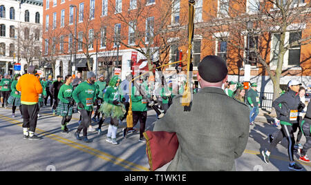 Ein Mann spielt Dudelsack in den Straßen der Innenstadt von Cleveland, Ohio USA als Teilnehmer der 2019 St. Patrick's Day Kilt Rennen vorbei. Stockfoto