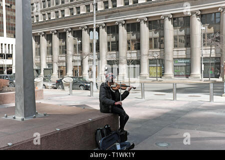 Ein einsamer Straßenmusikant spielt eine Violine an der Ecke Euclid Avenue und East 9. in der Innenstadt von Cleveland, Ohio, USA. Stockfoto