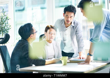 Gruppe von vier jungen asiatischen Führungskräfte treffen im Büro diskutieren im Büro. Stockfoto