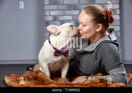 Junge schöne Frau, ihr Französisch Bulldog Welpen Umarmungen und Küsse ihn - Liebe, Freundschaft Konzept Stockfoto