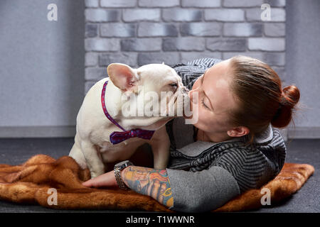 Junge schöne Frau, ihr Französisch Bulldog Welpen Umarmungen und Küsse ihn - Liebe, Freundschaft Konzept Stockfoto