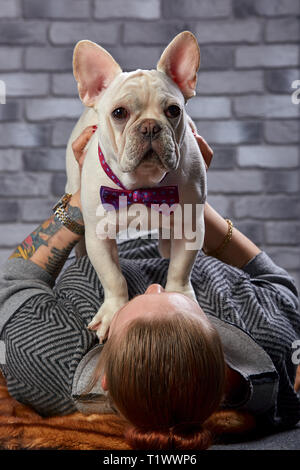 Junge schöne Frau, ihr Französisch Bulldog Welpen Umarmungen und Küsse ihn - Liebe, Freundschaft Konzept Stockfoto