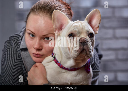 Junge schöne Frau, ihr Französisch Bulldog Welpen Umarmungen und Küsse ihn - Liebe, Freundschaft Konzept Stockfoto
